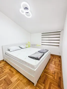 Bright bedroom with a double bed, wooden parquet flooring, and a window. - image 6