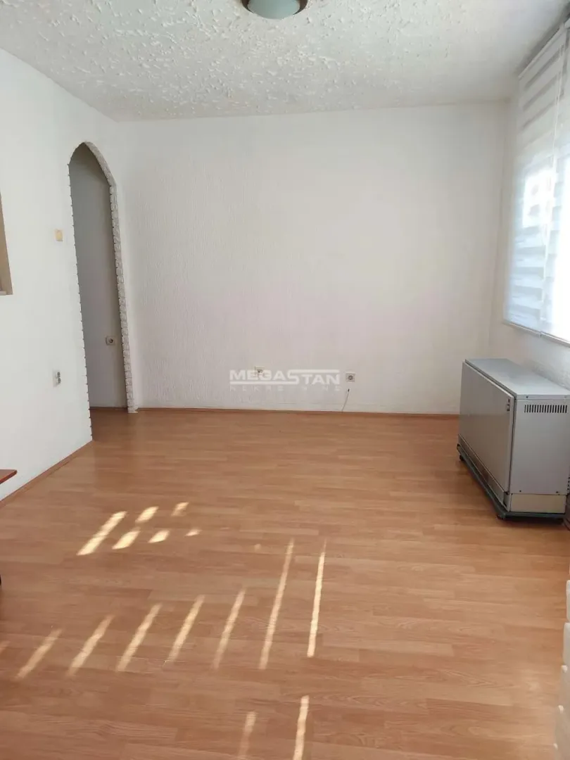 Prazna prostorija sa laminatom, belim zidovima i prozorom.