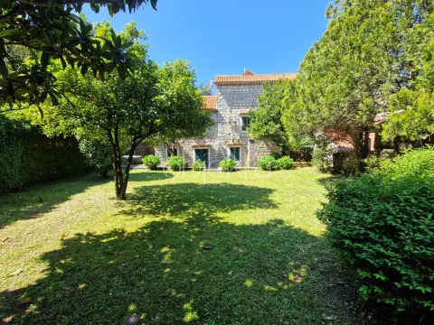 Green yard with lawn and trees in front of a stone house. - image 6