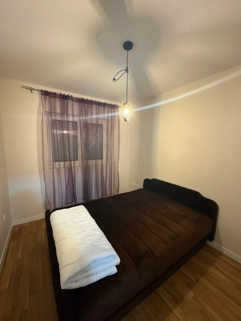 A bedroom with a double bed and a window with purple curtains.