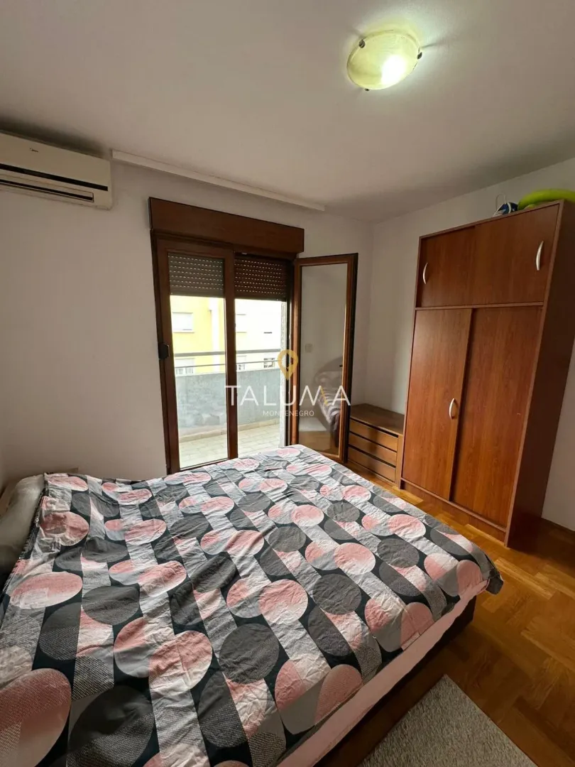 Furnished bedroom with a double bed, wooden wardrobe and access to the terrace.
