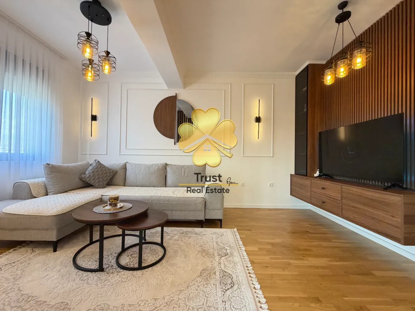 Modern and bright living room with a sectional sofa, wooden wall panels, and a TV unit.