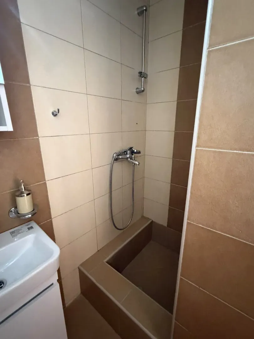 Bathroom with a shower cabin and sink in beige and brown tones.