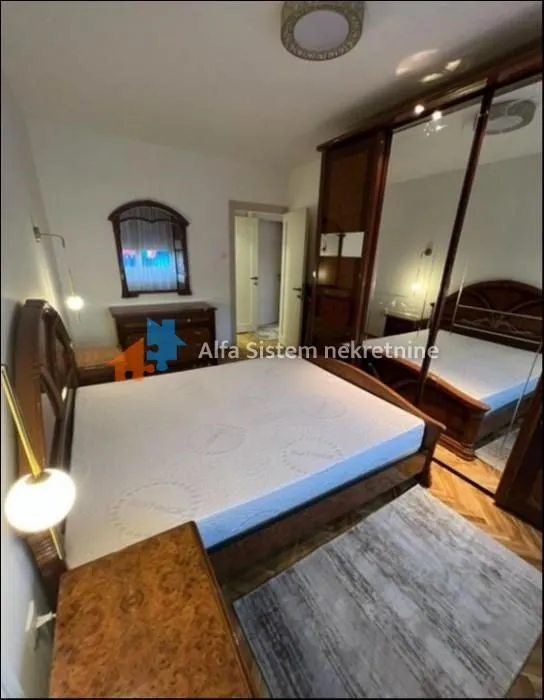 Furnished bedroom with a double bed, large wardrobe, and chest of drawers.