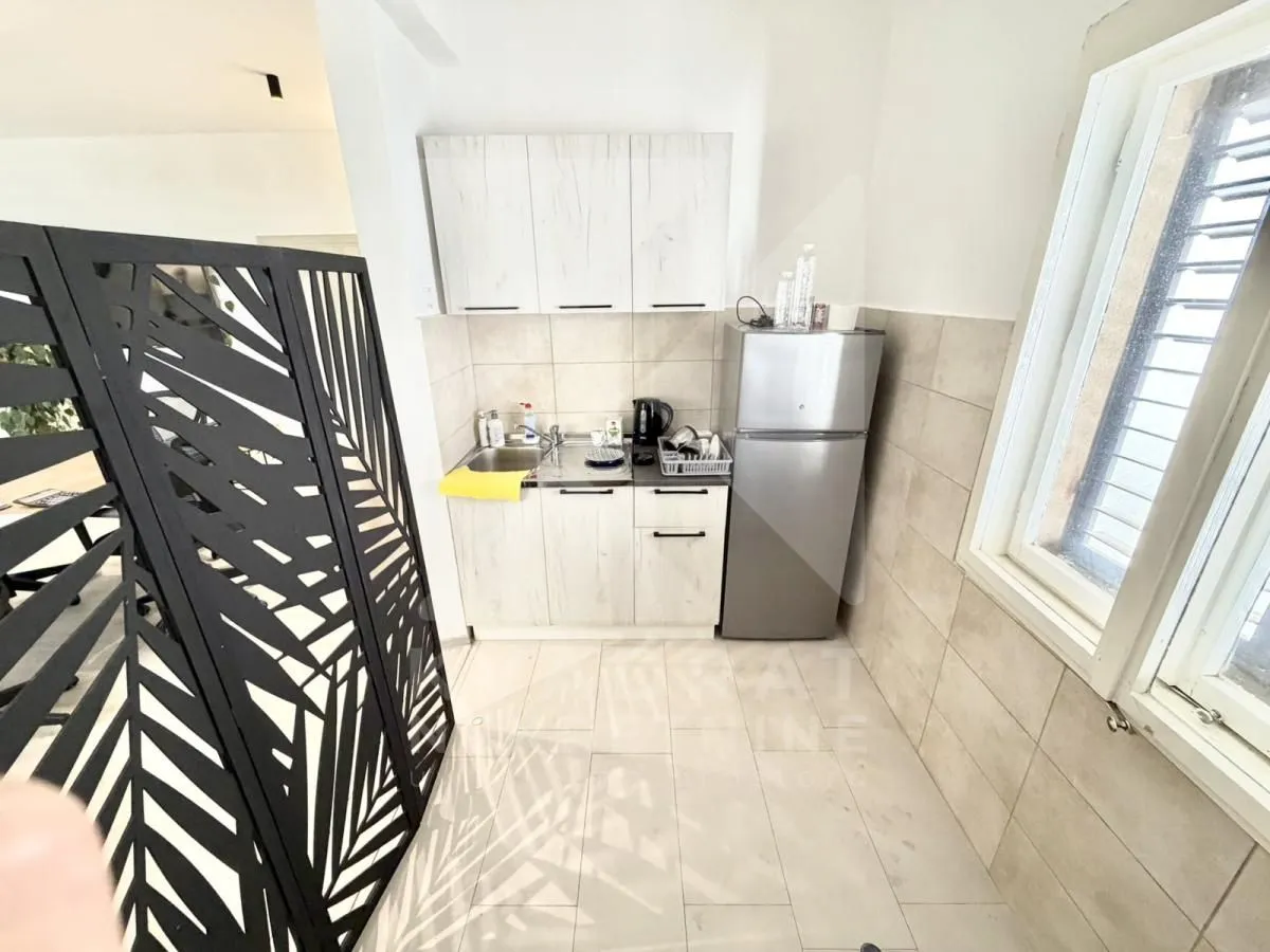 Small kitchen with white cabinets, a refrigerator, and a window.