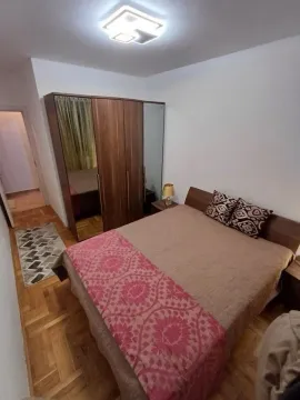 Spavaća soba sa bračnim krevetom i drvenim ormarom. - image 3
