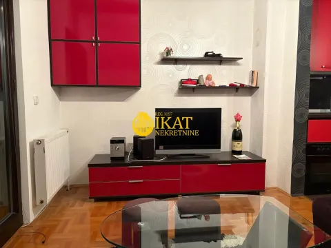 Dnevni boravak sa crvenim elementima, televizorom i policama na zidu. - image 4