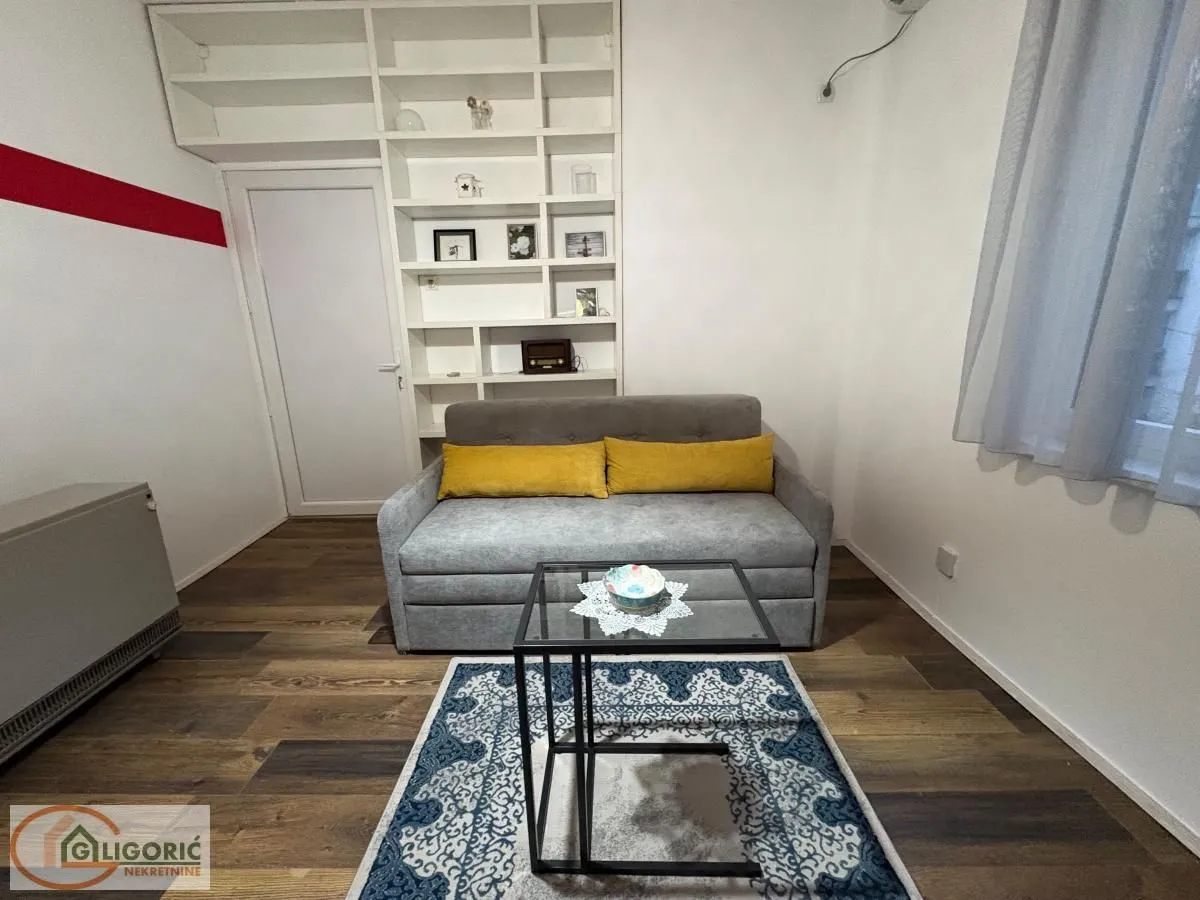 Small living room with a grey sofa, coffee table and built-in wall shelves.