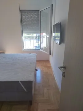 Manja spavaća soba sa bračnim krevetom, parketom i otvorenim prozorom. - image 4