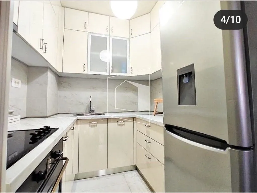 Compact kitchen with light cabinets and built-in appliances.