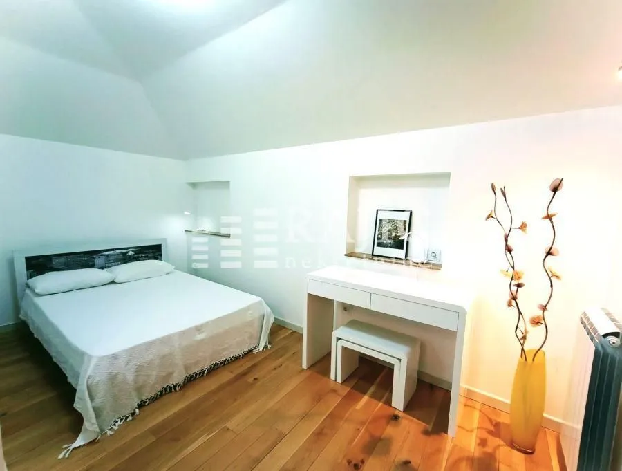 Furnished bedroom with a double bed and wooden flooring.