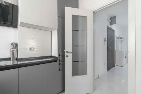 View of a modernly equipped kitchen with white and grey cabinetry and an open passage to the hallway. - image 14