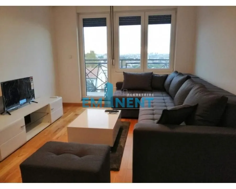Living room with a sectional sofa, TV, and access to the terrace.