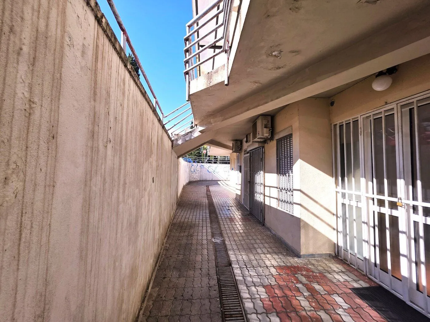 Exterior passageway next to the building entrance with paved flooring.