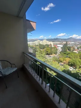 Pogled sa natkrivenog balkona na okolne zgrade, zelenilo i planine. - image 2