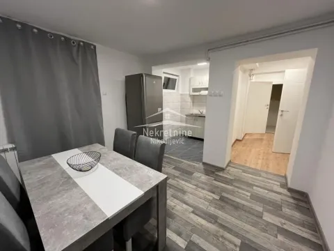 Dining area with table and chairs, with a view of the kitchen in the background. - image 2