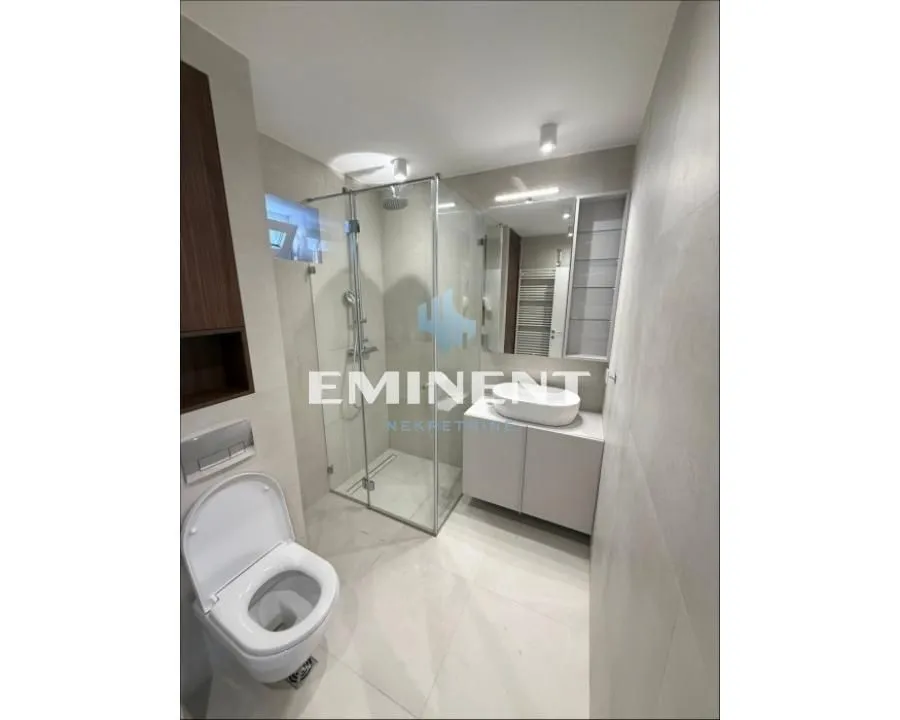 Modern bathroom with a walk-in shower, washbasin, and toilet.