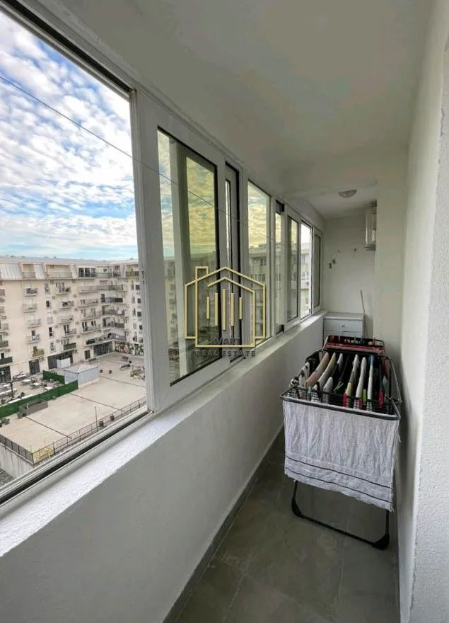 Zastakljeni balkon sa sušilicom za veš i pogledom na naselje.