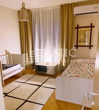 Children's bedroom with two beds, a rug, and a large window. - image 11