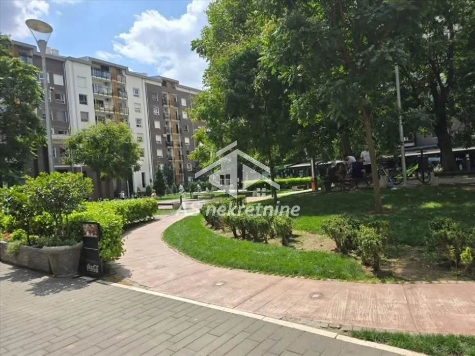 Landscaped courtyard with a pathway, greenery, and trees in front of the residential building.