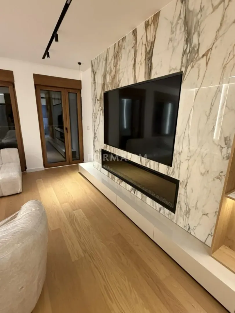Living room with wall-mounted TV and marble cladding.