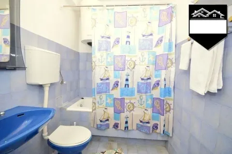 Small bathroom tiled in blue with a bathtub and a shower curtain. - image 6