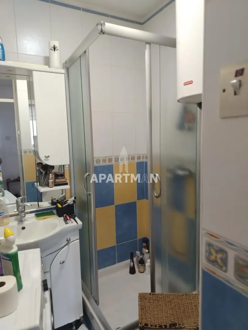 Kupatilo sa tuš kabinom, umivaonikom i ormarićem sa ogledalom.