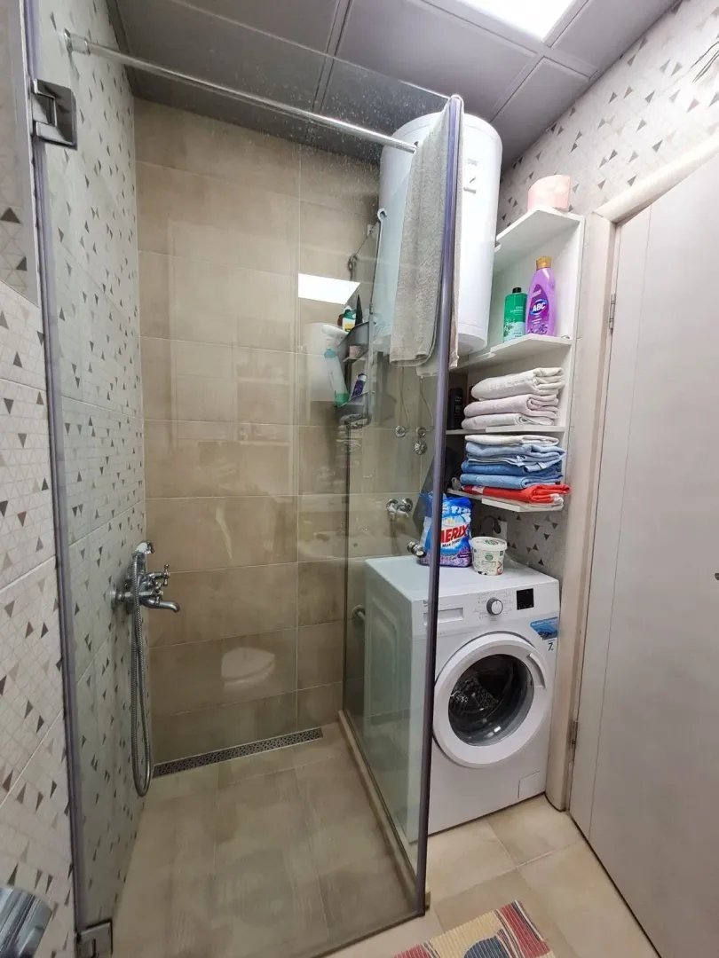 Compact bathroom with a shower cabin and washing machine.