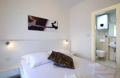 Furnished bedroom with a double bed and a view into the bathroom. - image 9
