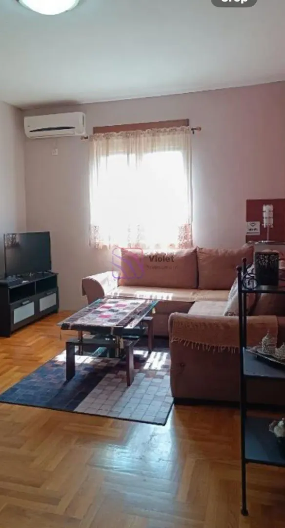 Dnevna soba sa garniturom, stočićem i televizorom.