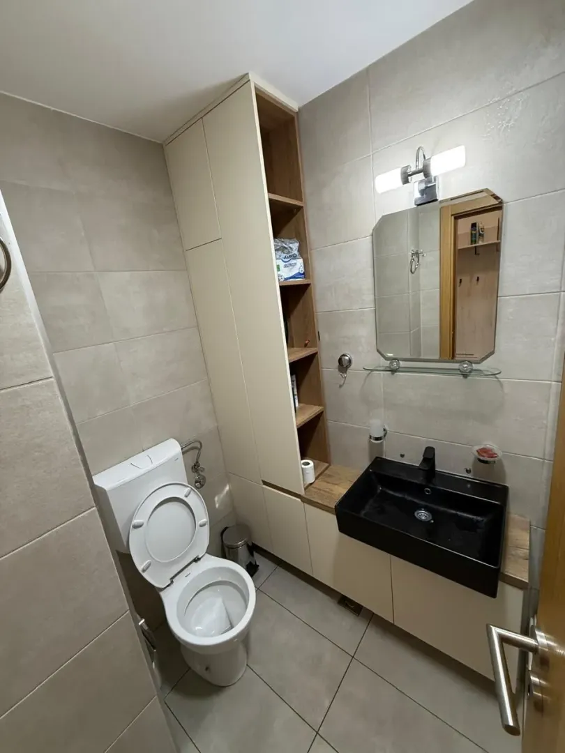 Modernly equipped bathroom with a sink, toilet, and built-in storage units.