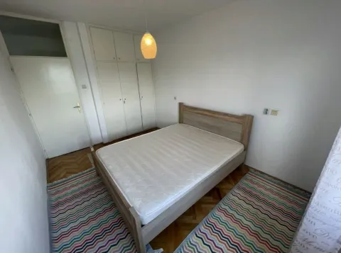 Spavaća soba sa bračnim krevetom, ormarom i drvenim podom. - image 4