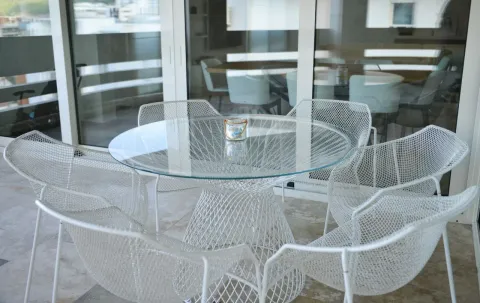 Natkrivena terasa sa okruglim stolom i modernim mrežastim stolicama. - image 20