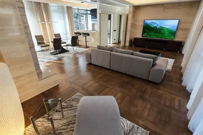 Spacious living room with a sofa, TV and dining area in the background.