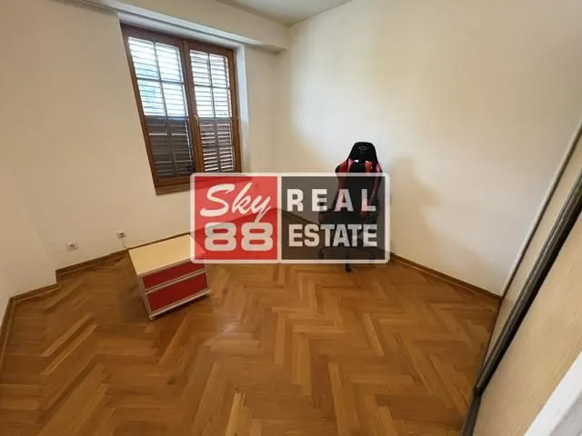 Empty room with parquet flooring and a single window.