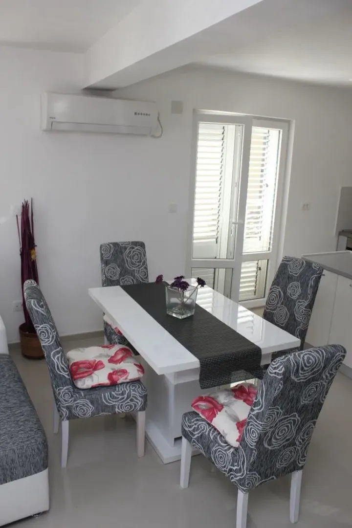 Dining area with a white table and grey patterned chairs.