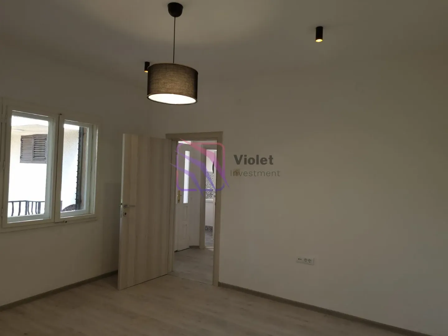 Empty room with white walls, a window, and a door leading to the hallway.