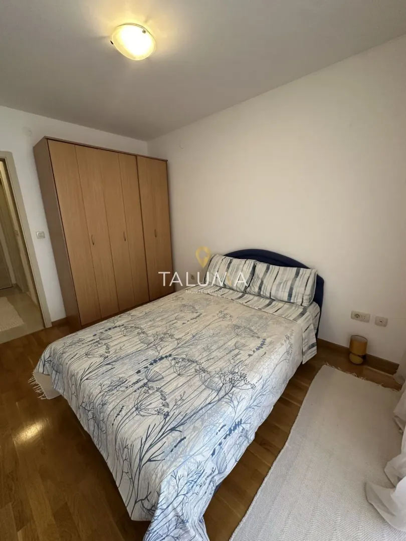 Furnished bedroom with a double bed and a wooden wardrobe.
