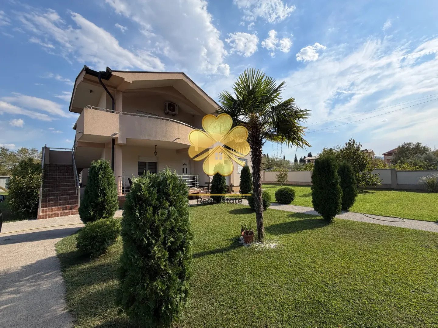 Exterior of a two-story house with a landscaped yard, lawn, and a palm tree.