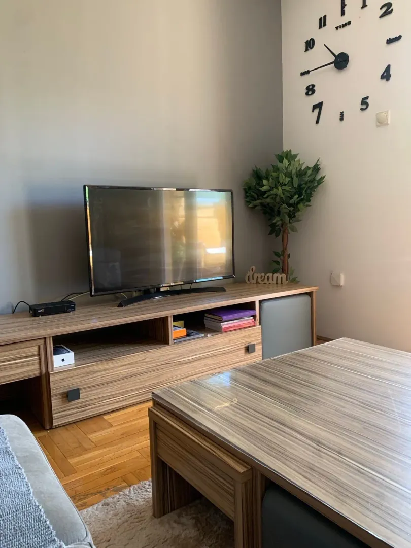 Living room with a wooden TV cabinet, television, and dining table.