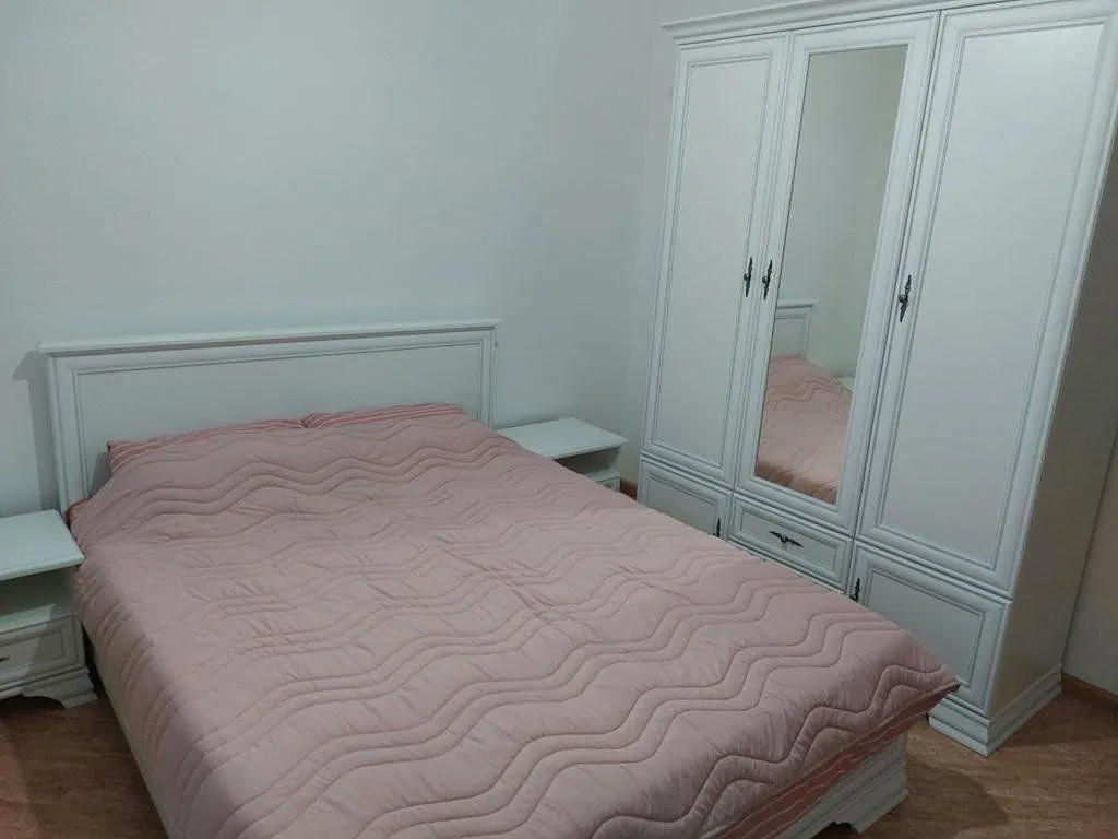 Furnished bedroom with a double bed, a white wardrobe, and bedside tables.