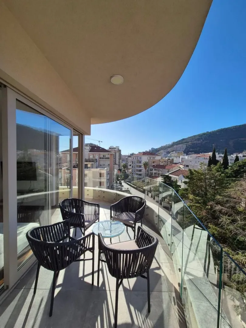 Furnished balcony with seating set and a view of the city and hills.