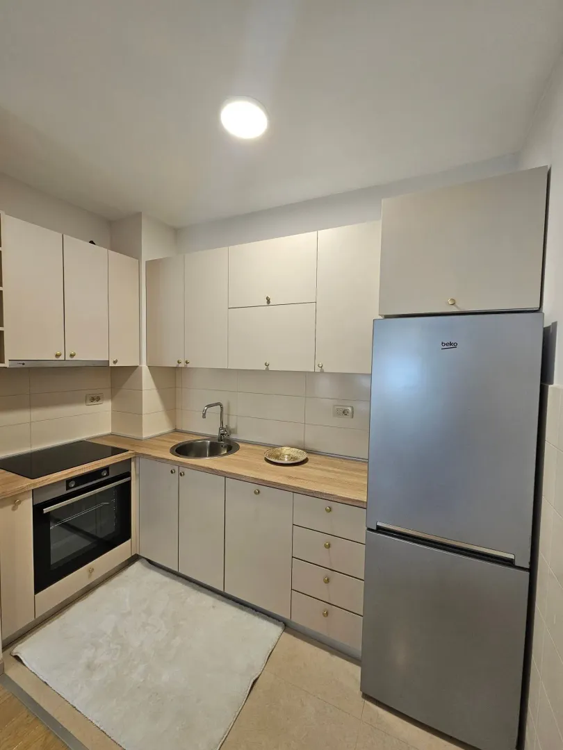 Small modern kitchen with light-colored cabinetry and a refrigerator.
