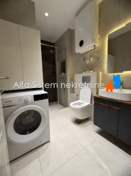 Modernly equipped bathroom with a walk-in shower, washing machine, and built-in fixtures. - image 4