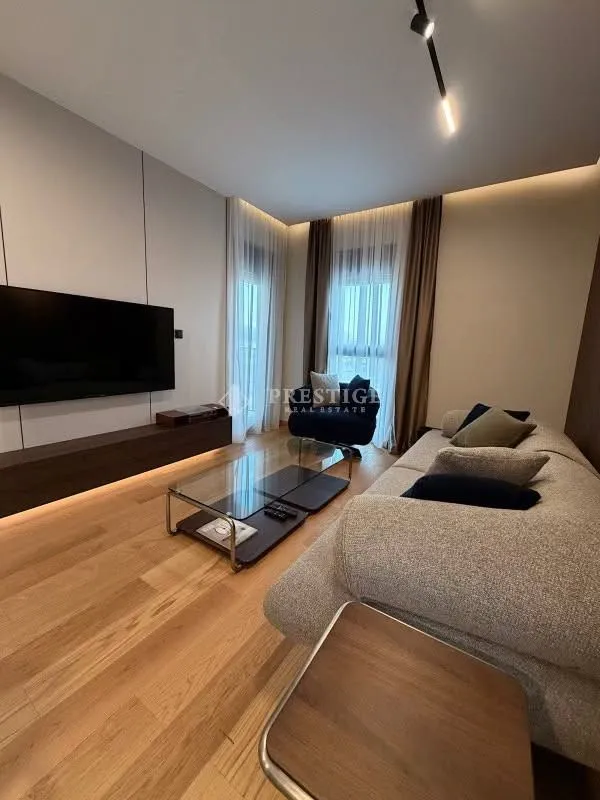 Modern living room with a sofa, TV, and wooden flooring.