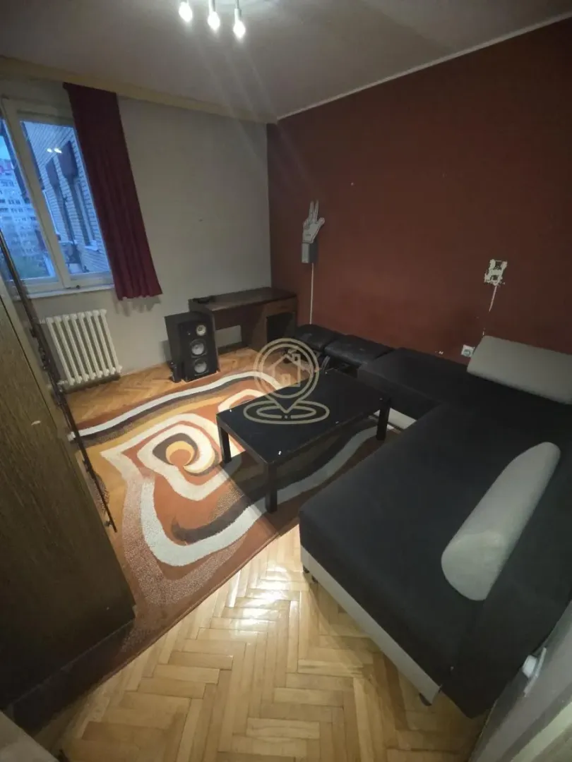 Dnevna soba sa garniturom, tepihom i prozorom.