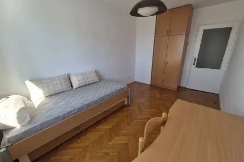 Small bedroom with a bed, wooden wardrobe, and a desk. - image 6