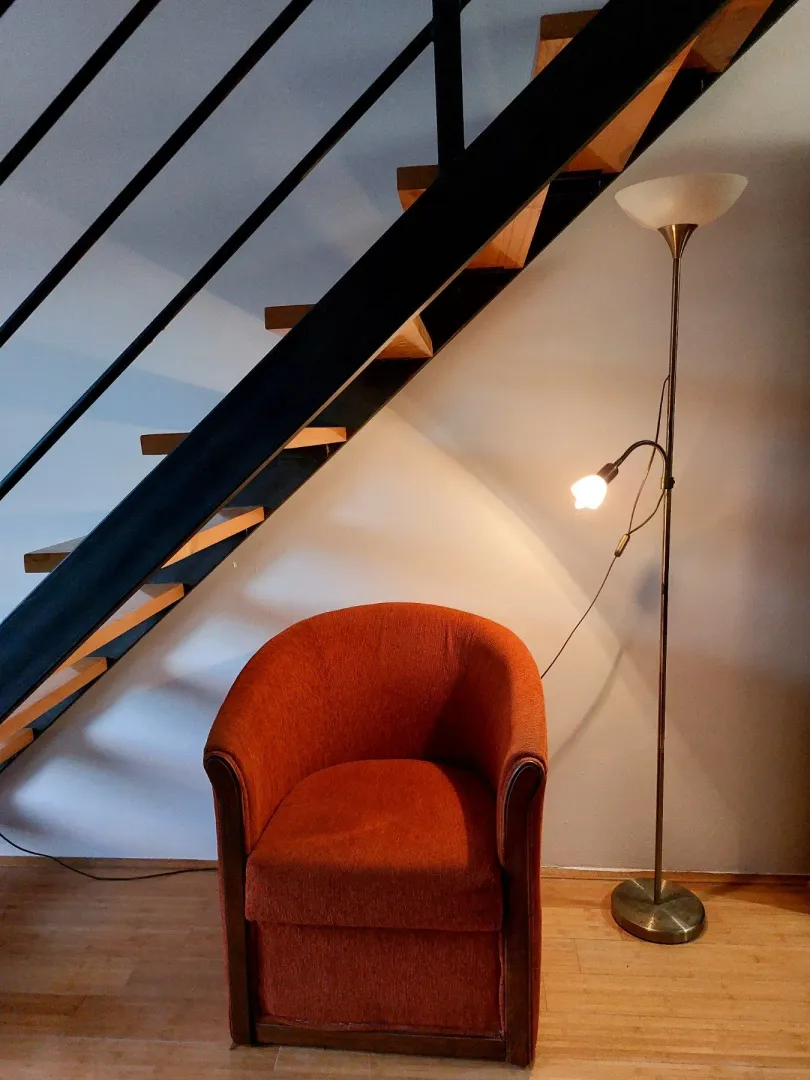 Comfortable armchair and floor lamp next to the staircase in the living room.