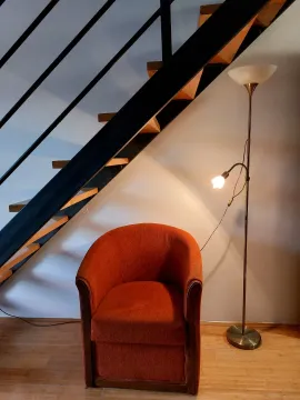 Comfortable armchair and floor lamp next to the staircase in the living room. - image 4
