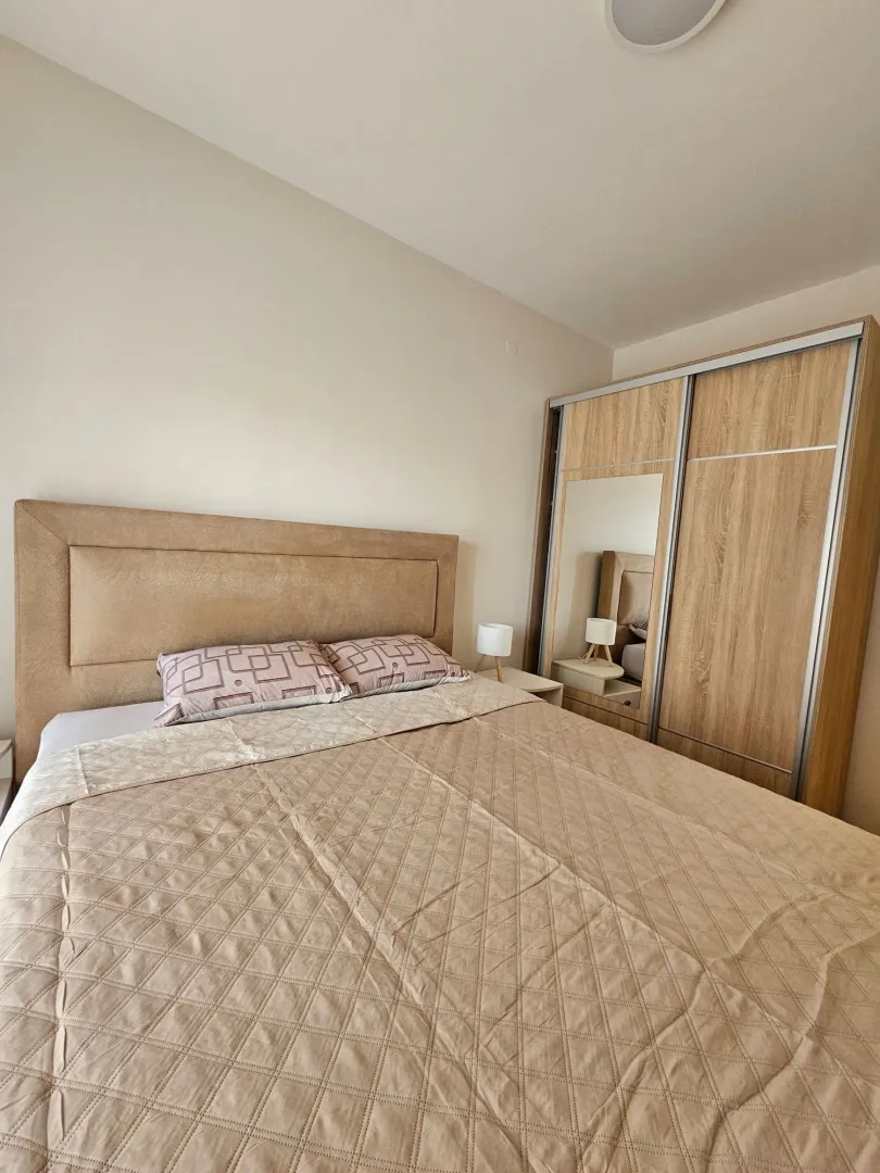 Furnished bedroom with a double bed and a wooden wardrobe.